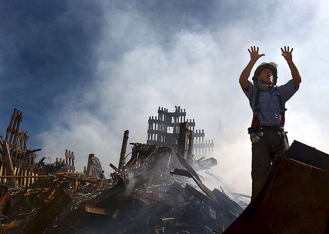 A fireman calls for 10 more colleagues amidst the ruins of the World Trade Centre, 10 September 2001. US Navy, Public Domain, via Wikimedia Commons.
